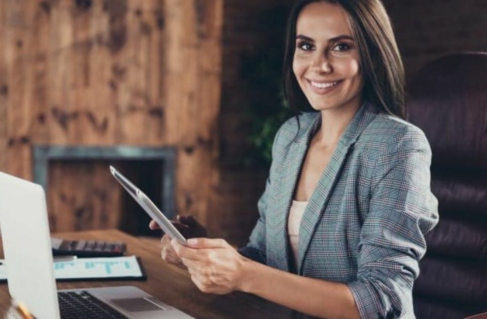 assistante de direction face à un ordinateur avec un stylo dans la main