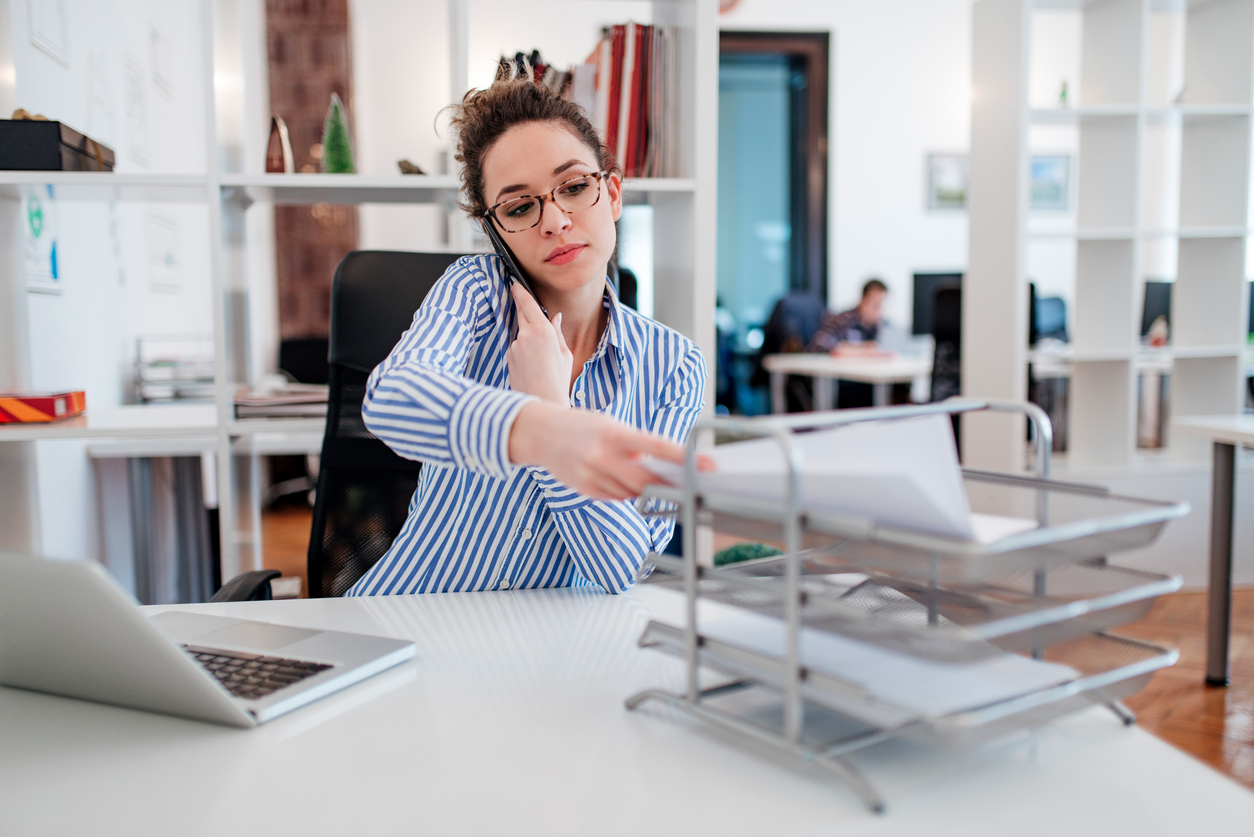 Une assistante juridique au bureau fait de la paperasse et parle au téléphone