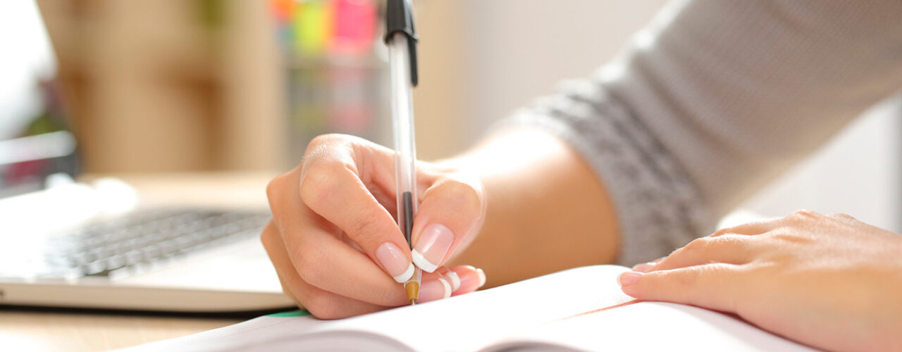 main droite écrivant sur un cahier avec un stylo